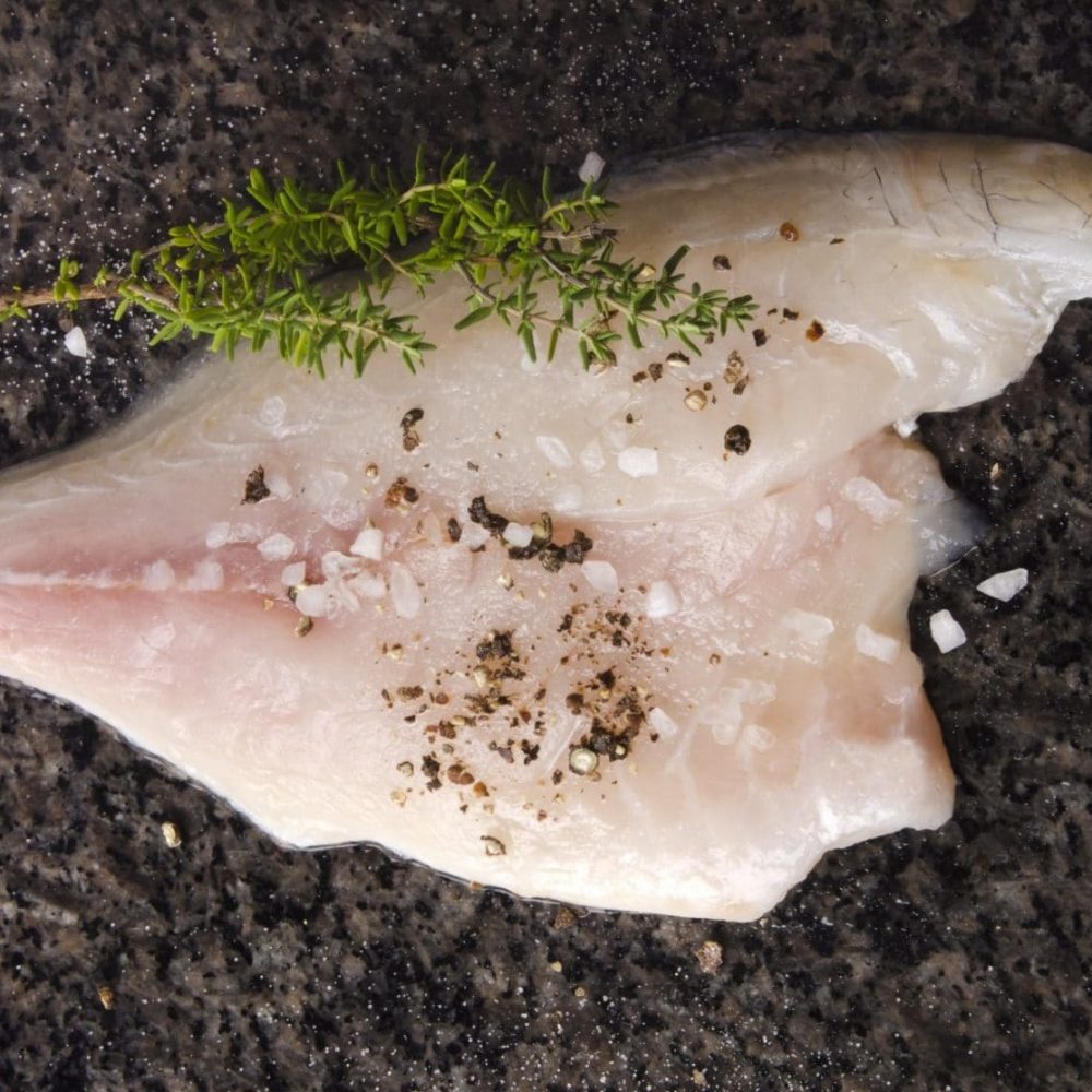 sea bream fillet with spice mix on a dark marble surface