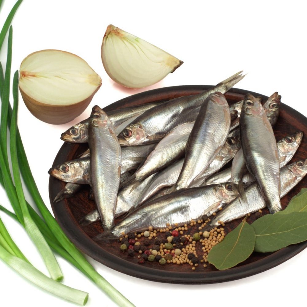 Sprat spicy salting in a plate, onions and green onions